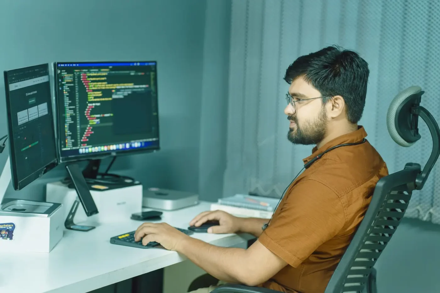 Developer writing code across two monitors Website development services: developer writing code across two monitors