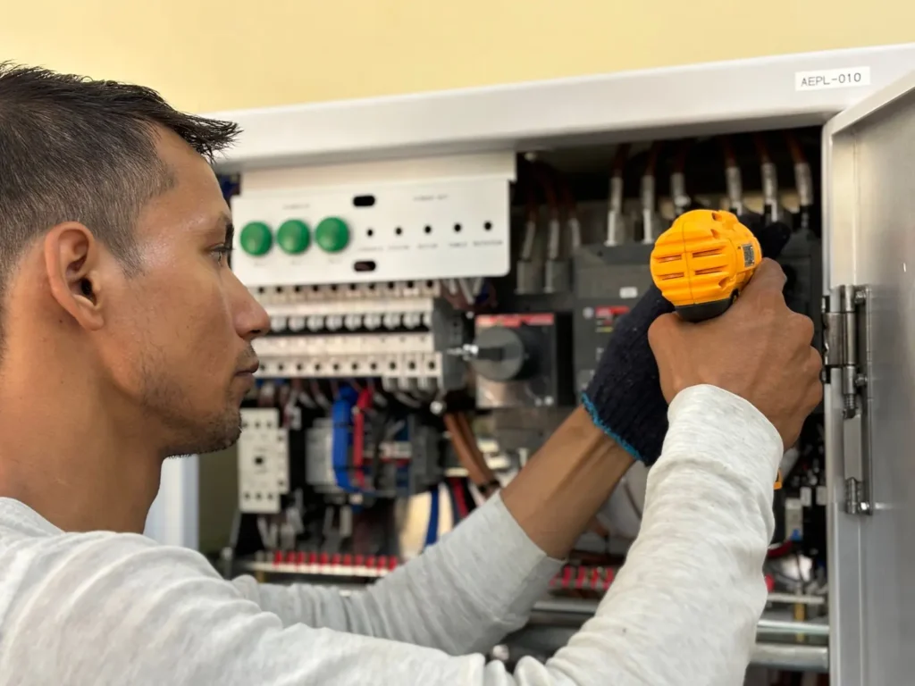 Electrician using a drill on an electrical panel Local SEO New Jersey: electrician using a drill on an electrical panel