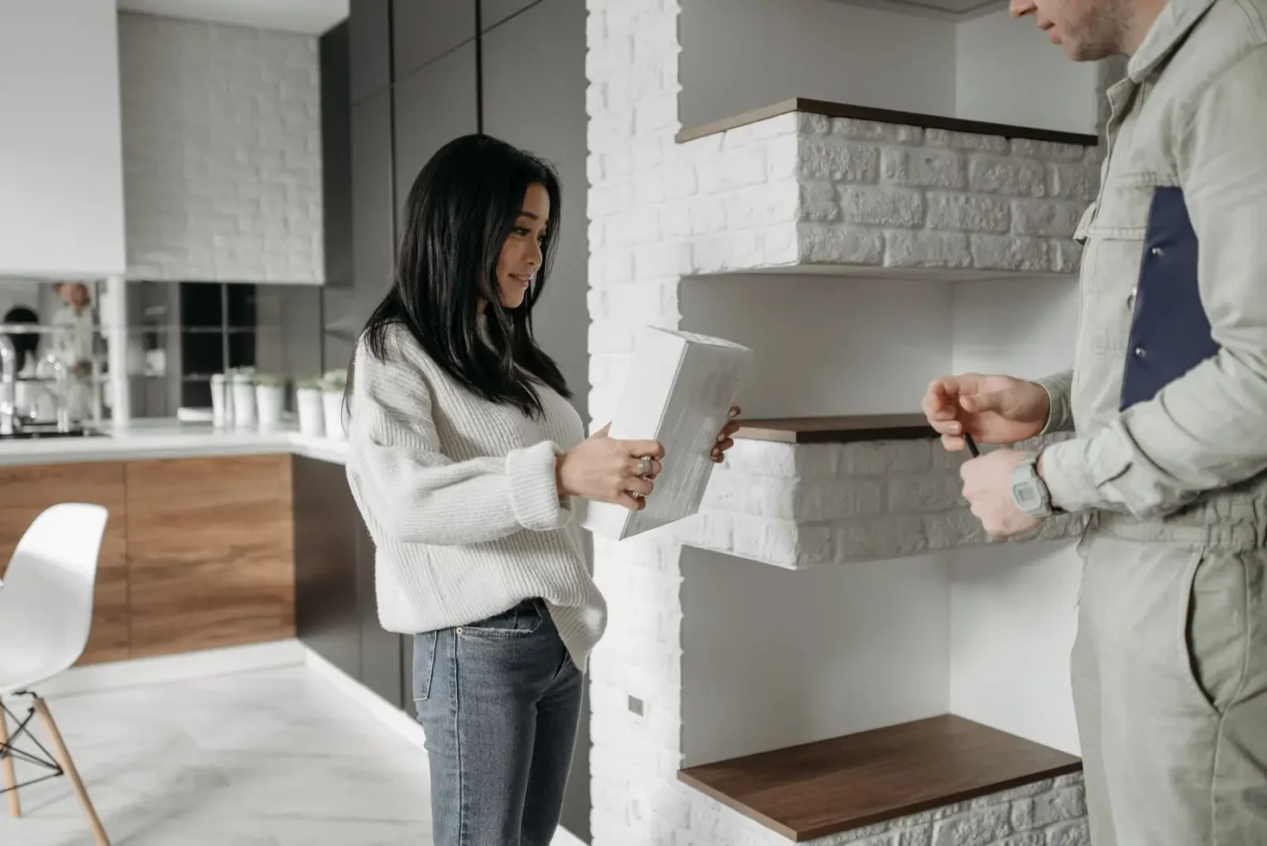 Homeowner holding a tablet while talking with a service technician in her kitchen Home services marketing: homeowner holding a tablet while talking with a service technician in her kitchen