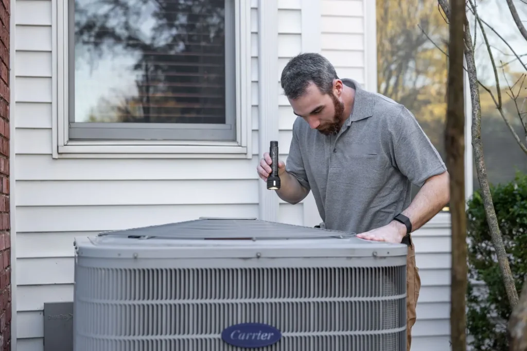 Local SEO Boise: HVAC technician inspecting an outdoor air conditioning unit beside a home