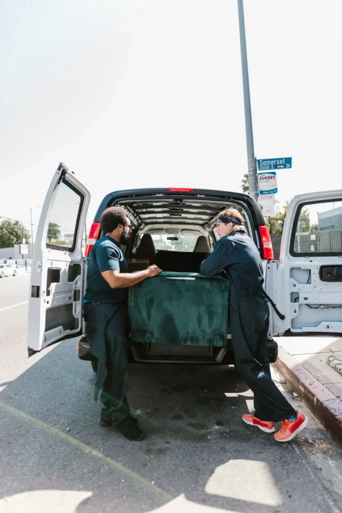 Two workers loading a sofa into the back of a van Junk removal marketing: two workers loading a sofa into the back of a van