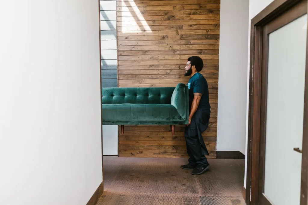 Moving company marketing: mover carrying a green sofa through a doorway