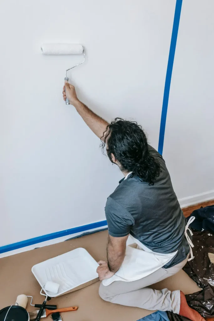 Painting company marketing: painter rolling a wall beside fresh painter's tape