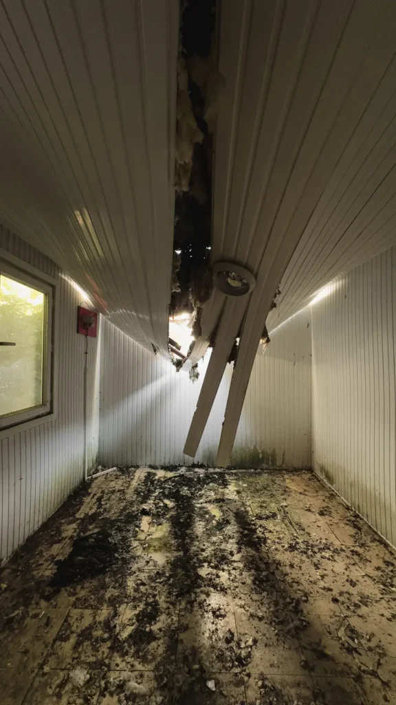 Hallway with a collapsed ceiling and debris after water damage Restoration marketing: hallway with a collapsed ceiling and debris after water damage