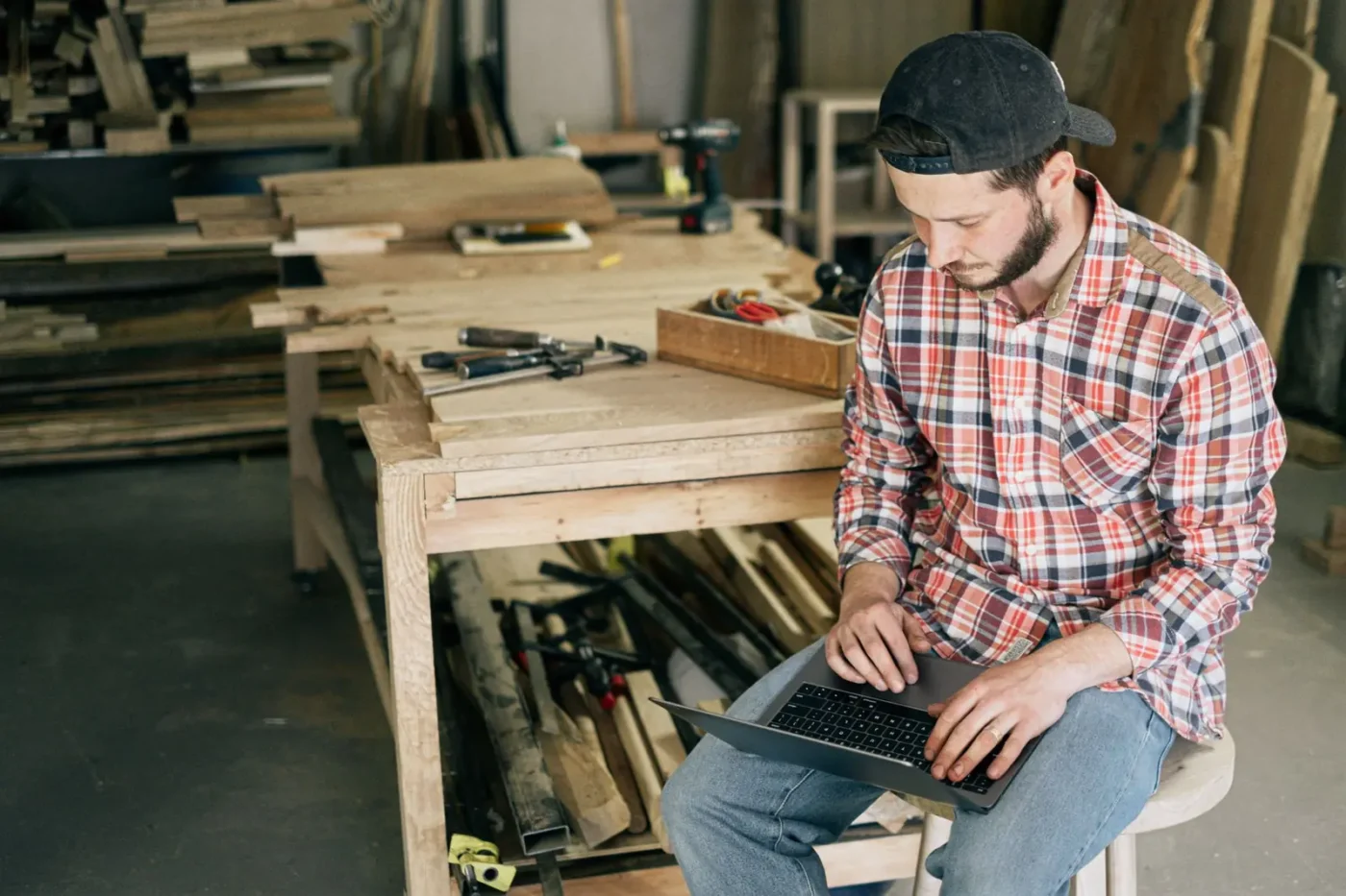 Tradesman in his workshop checking his laptop Google Ads management: tradesman in his workshop checking his laptop
