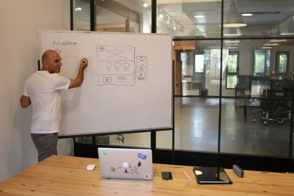 Strategist sketching a website wireframe on a whiteboard Conversion rate optimization services: strategist sketching a website wireframe on a whiteboard